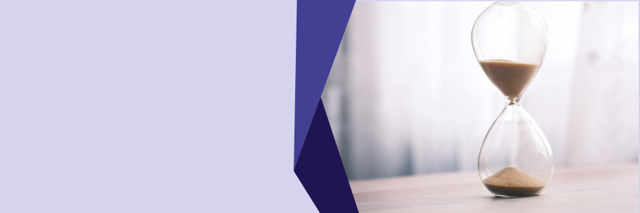 Minimal banner image featuring a glass hourglass with sand flowing on a light wooden surface, framed by a soft abstract purple shape, representing the urgency and limited time for family business succession planning.