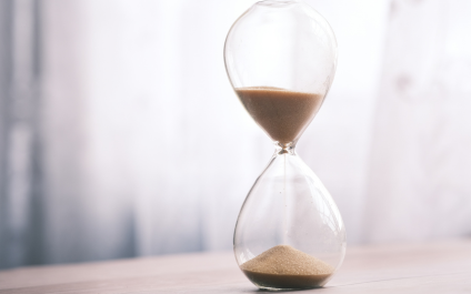Hourglass with sand steadily flowing from the top chamber to the bottom, symbolizing time passing and the urgency of planning before opportunities run out.